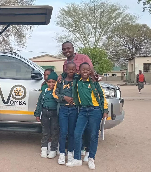 A teacher standing with his students at a safari lodge